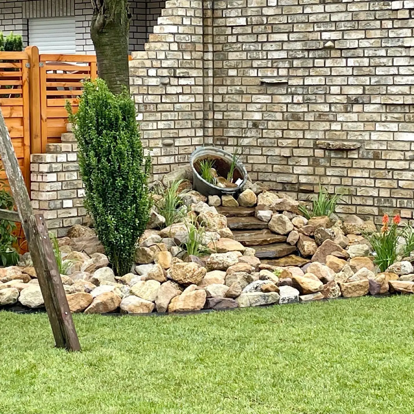 Kleiner dekorativer Gartenbrunnen, der dem Garten eine stilvolle und beruhigende Atmosphäre verleiht.
