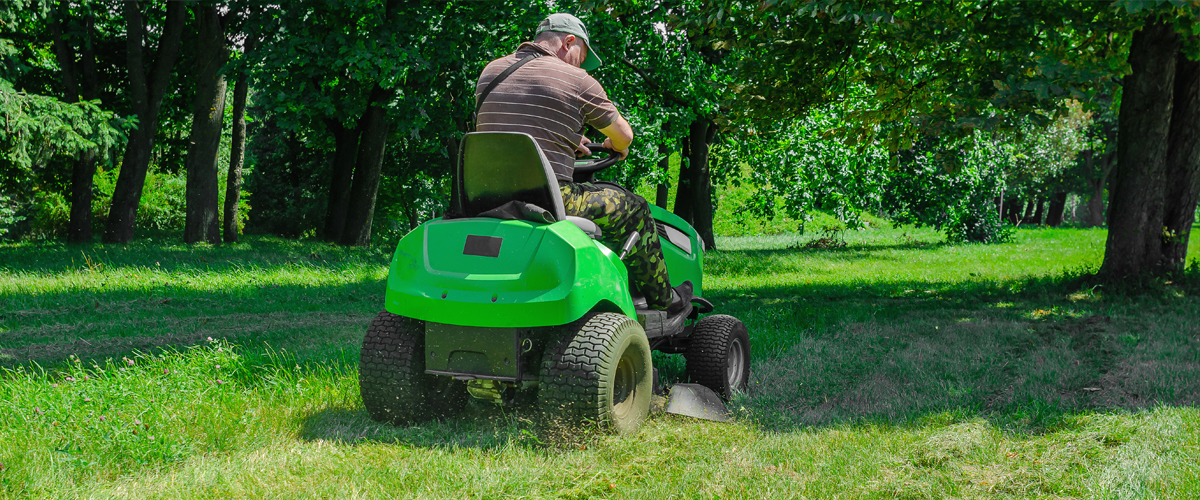 Mitarbeiter mäht große Grünflächen mit einem Aufsitzmäher für ein gleichmäßiges und gepflegtes Rasenergebnis.